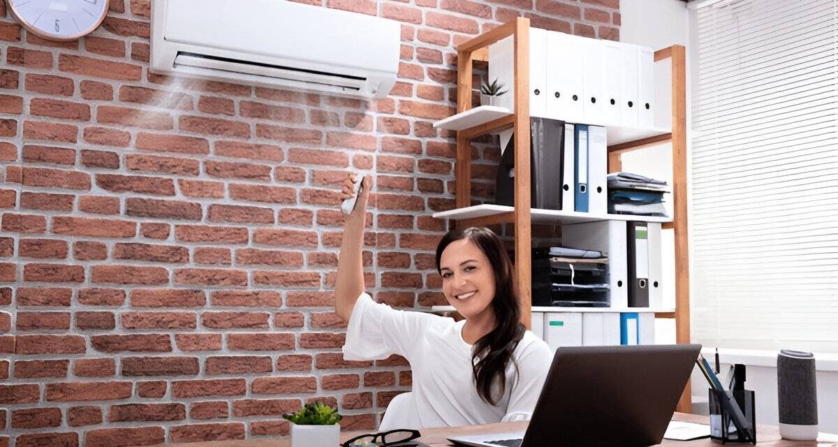 Woman using remote to control air conditioner in modern office, showcasing HVAC comfort solutions for homeowners in Bucks and Montgomery County.